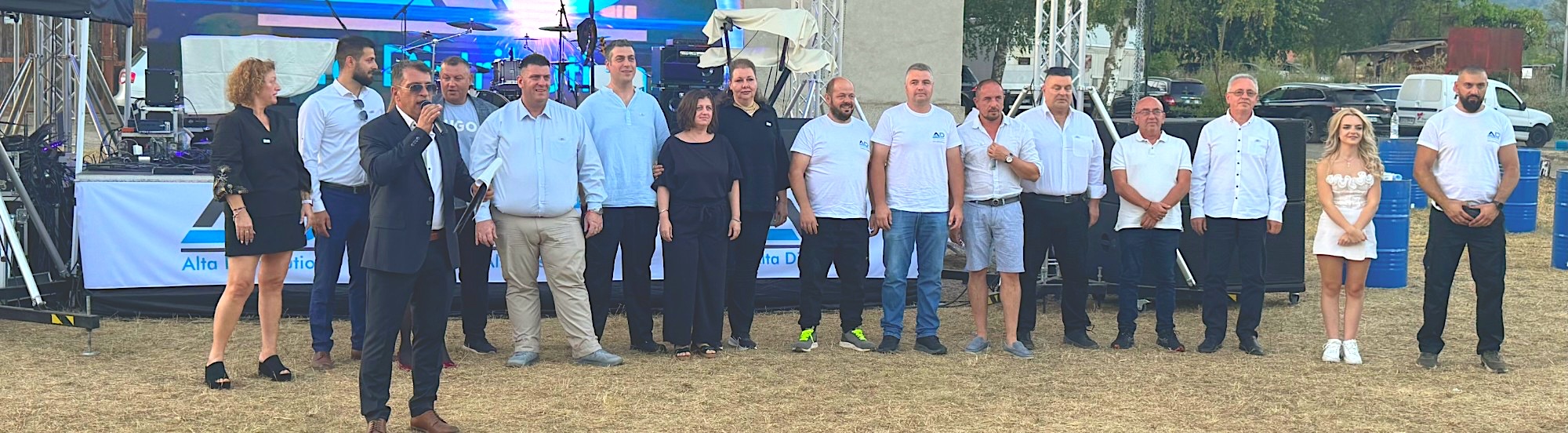 Team members standing together on an outdoor stage at a company event
